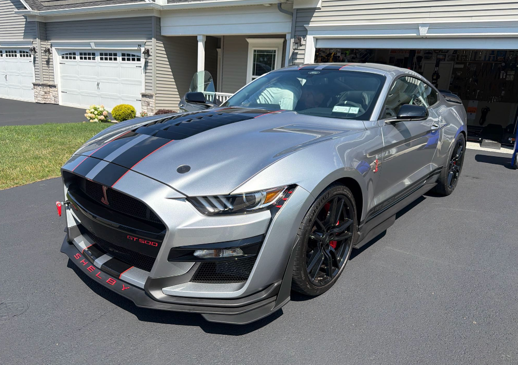 Silver Shelby GT500 Mustang in a driveway before Allstar Hauling transport