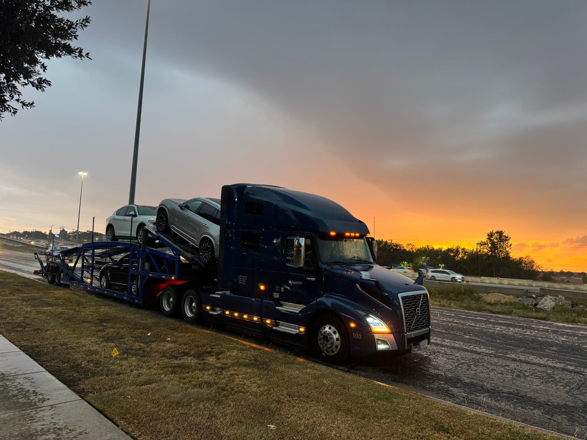 Navy Allstar Hauling Volvo VNL car hauler loaded with SUVs at sunrise along a Texas highway