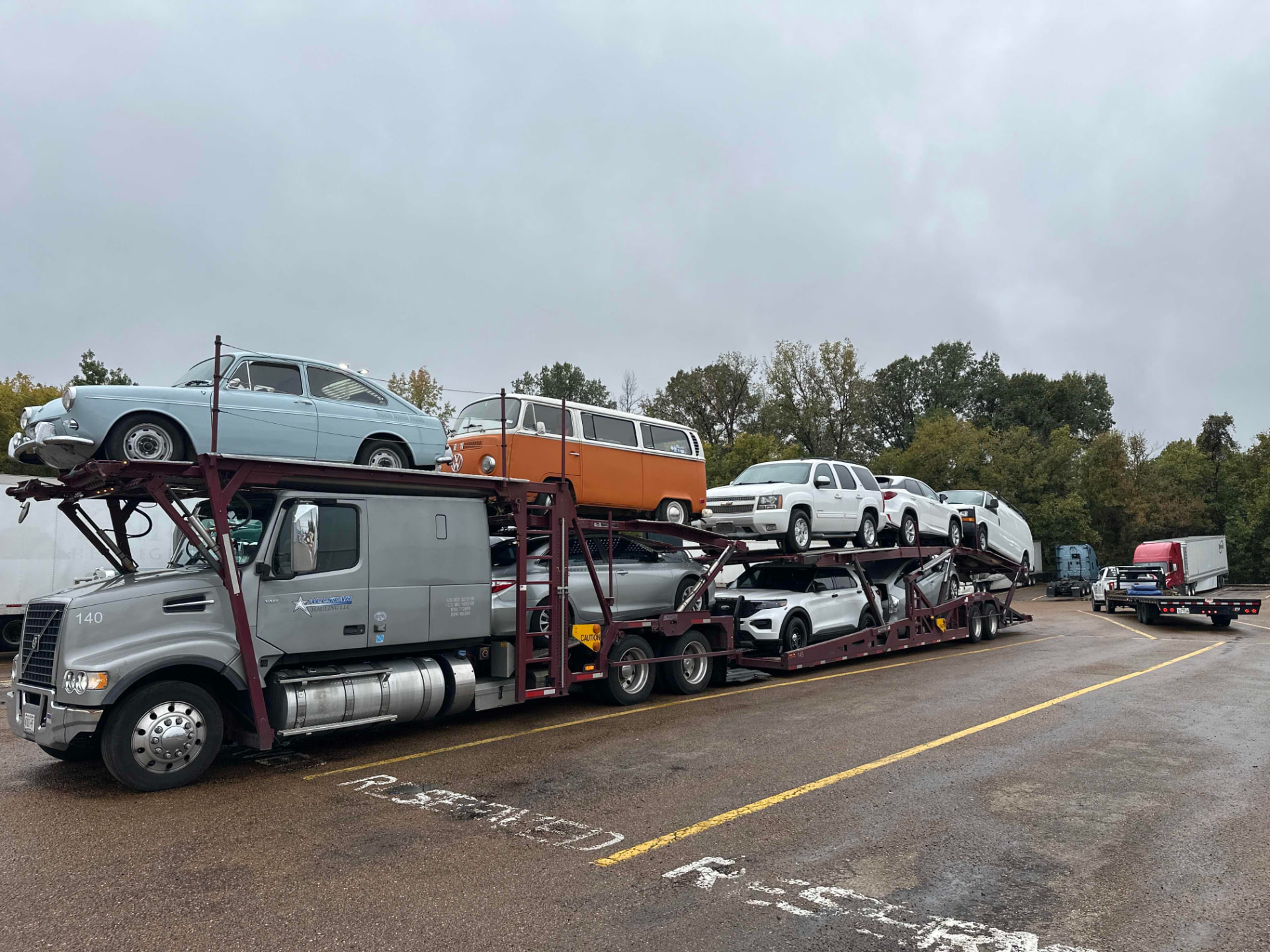 Gray Allstar Hauling Volvo carrier loaded with a classic Volkswagen bus, vintage sedan and SUVs