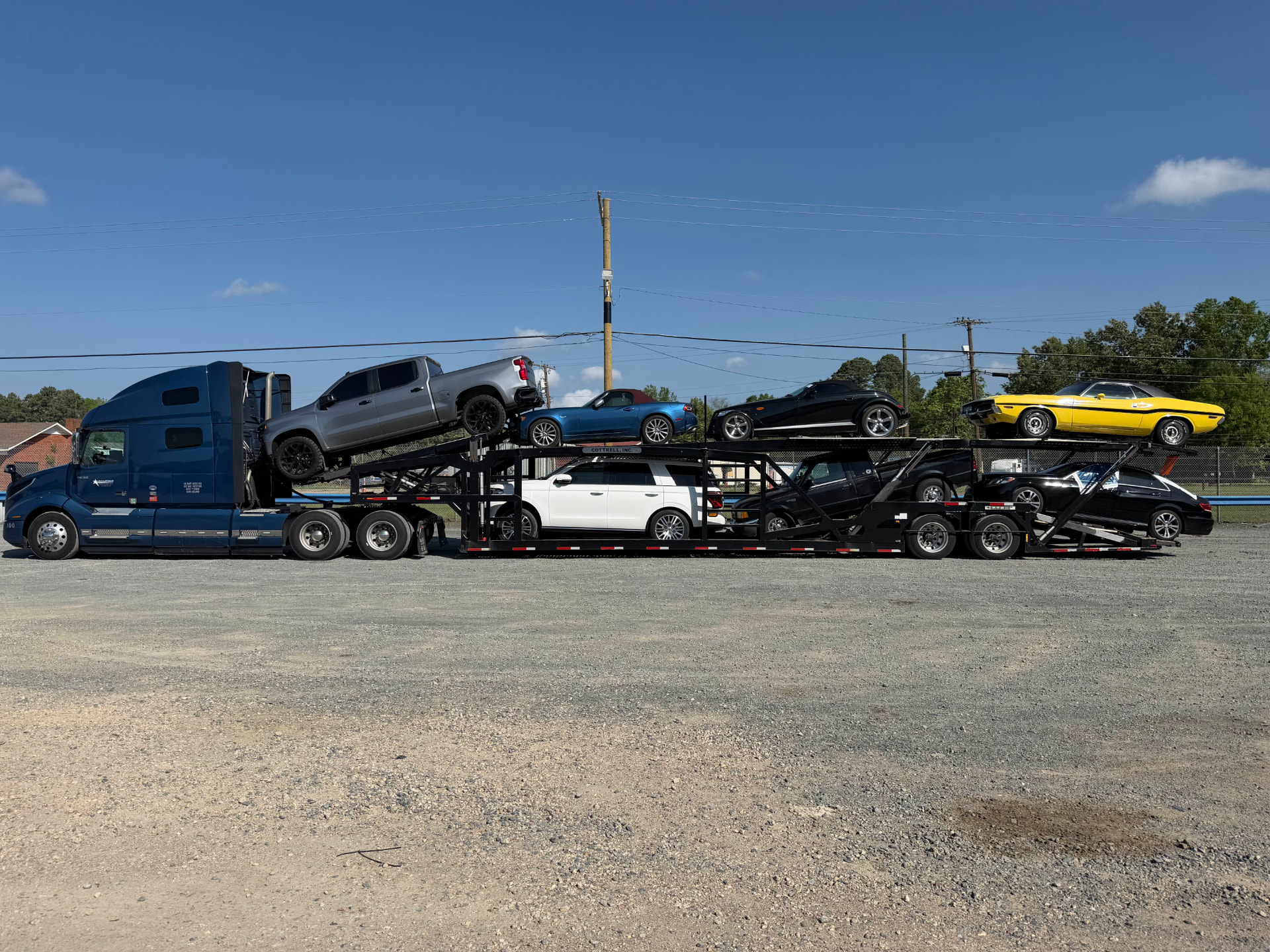 Blue Allstar Hauling Volvo carrier loaded with a Dodge Challenger, Plymouth Prowler, Miata and pickups