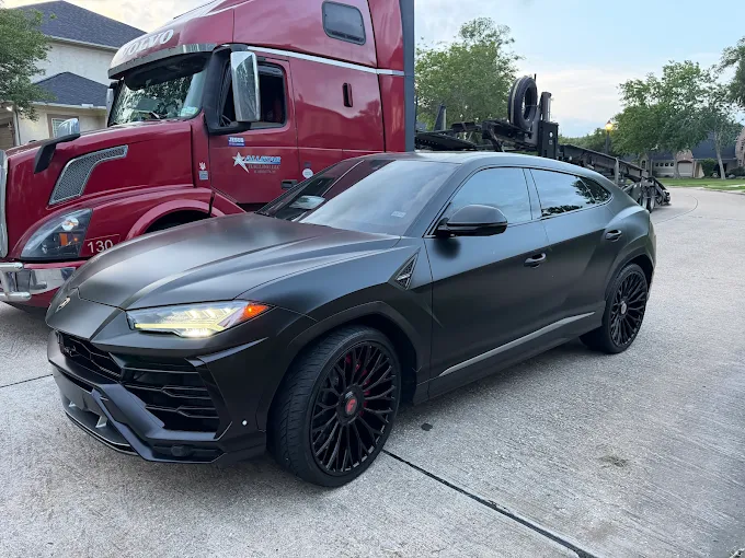 Satin black Lamborghini Urus beside an Allstar Hauling red Volvo car carrier